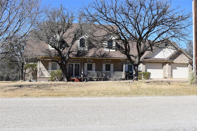 view of front of house with covered porch, brick siding, and an attached garage