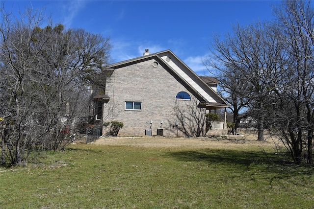 view of side of property featuring a yard, brick siding, and central AC