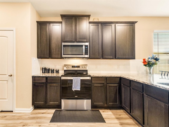 kitchen featuring light stone countertops, dark brown cabinets, light hardwood / wood-style flooring, and stainless steel appliances