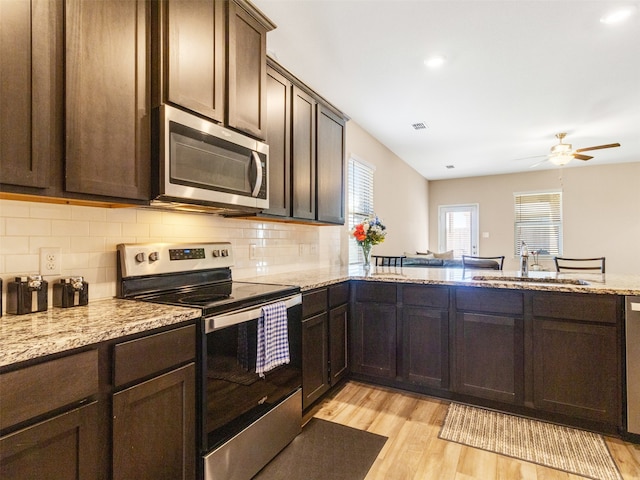 kitchen featuring tasteful backsplash, appliances with stainless steel finishes, light hardwood / wood-style floors, and sink