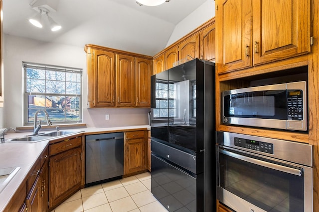 kitchen featuring lofted ceiling, sink, light tile patterned floors, and appliances with stainless steel finishes