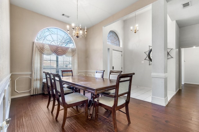 dining area featuring wood-type flooring, a towering ceiling, and a chandelier