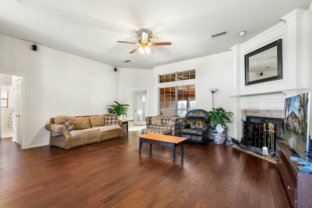 living room featuring dark wood-type flooring, ceiling fan, and a fireplace