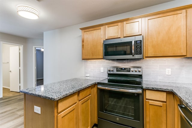 kitchen featuring light wood-type flooring, kitchen peninsula, stainless steel appliances, light stone countertops, and decorative backsplash