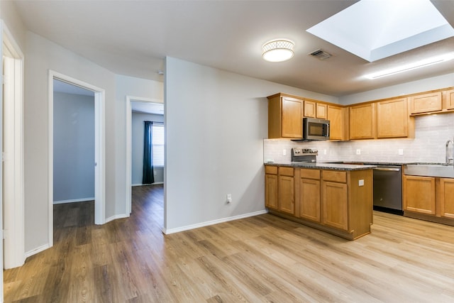 kitchen featuring light wood-type flooring, appliances with stainless steel finishes, sink, and backsplash