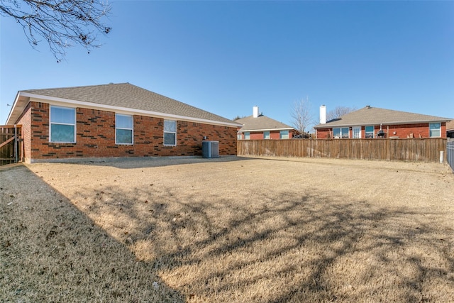 rear view of house featuring a yard and central AC