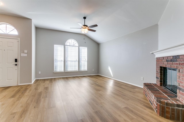 unfurnished living room featuring a brick fireplace, light hardwood / wood-style flooring, ceiling fan, and vaulted ceiling