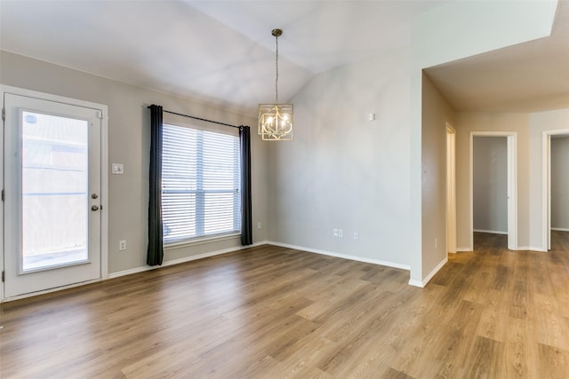 unfurnished dining area featuring vaulted ceiling, light hardwood / wood-style floors, and a chandelier