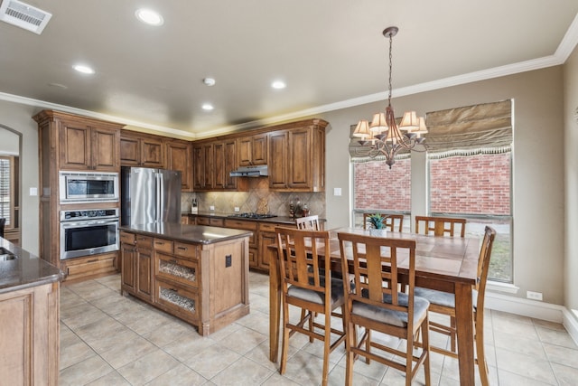 kitchen featuring appliances with stainless steel finishes, a chandelier, hanging light fixtures, a center island, and crown molding