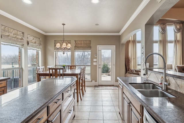 kitchen with light tile patterned flooring, sink, an inviting chandelier, crown molding, and pendant lighting