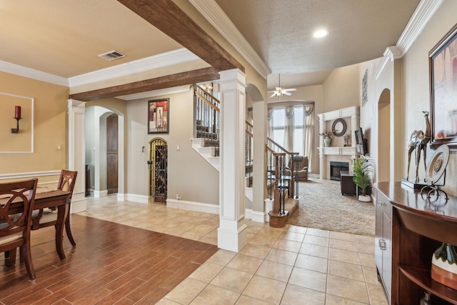 entryway with crown molding, ceiling fan, a textured ceiling, and ornate columns