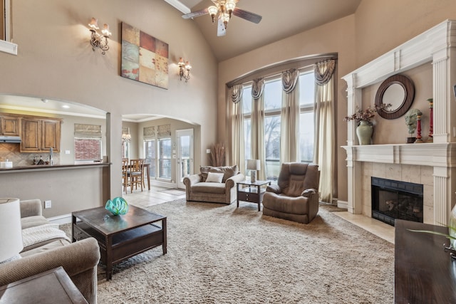 living room with a healthy amount of sunlight, a tiled fireplace, and light tile patterned floors