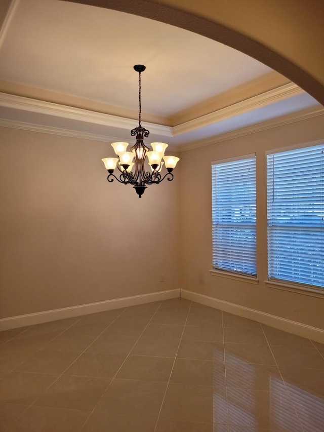 tiled spare room featuring crown molding, a notable chandelier, and a tray ceiling