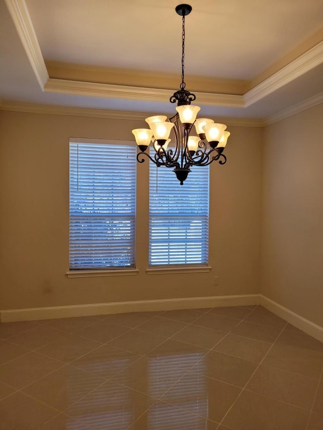 empty room with a notable chandelier, a tray ceiling, ornamental molding, and tile patterned floors