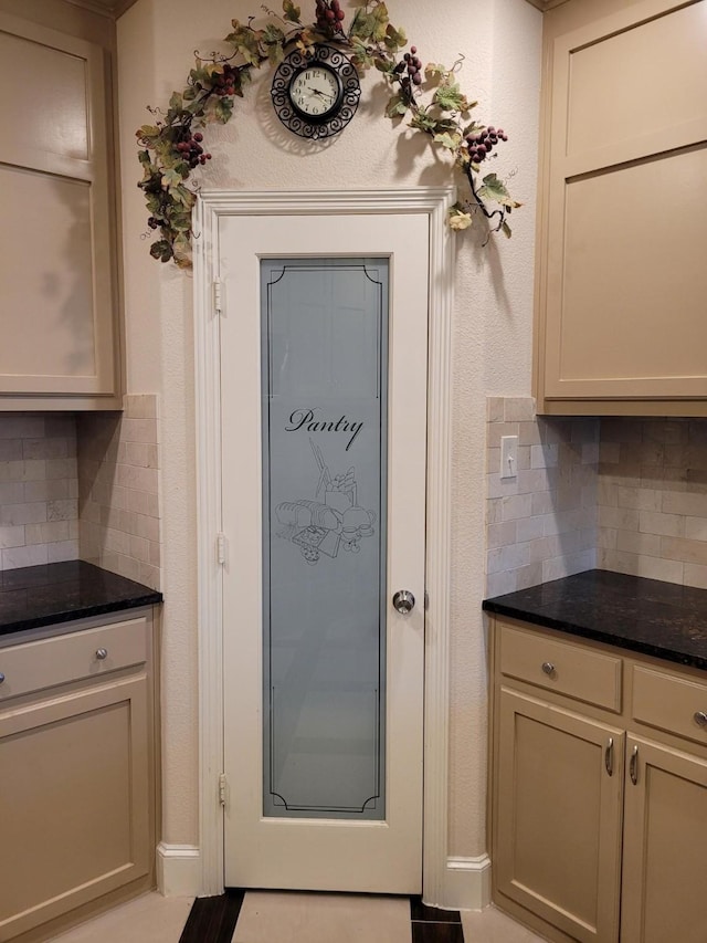 kitchen featuring light tile patterned flooring, cream cabinets, dark stone countertops, and backsplash