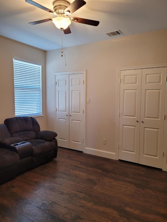 living room with dark hardwood / wood-style flooring and ceiling fan