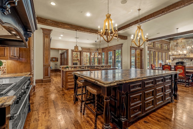 kitchen with dark hardwood / wood-style floors, decorative light fixtures, double oven range, beam ceiling, and a spacious island