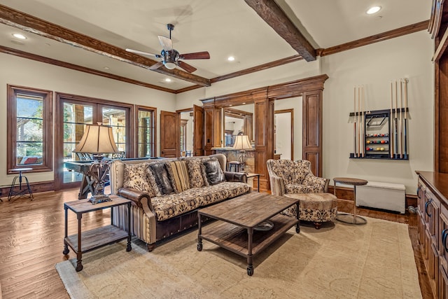 living room featuring beam ceiling, light hardwood / wood-style flooring, ornamental molding, and ceiling fan