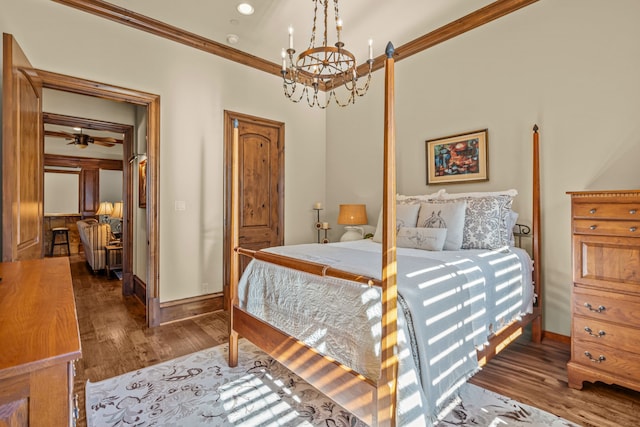 bedroom featuring crown molding, dark hardwood / wood-style floors, and a notable chandelier