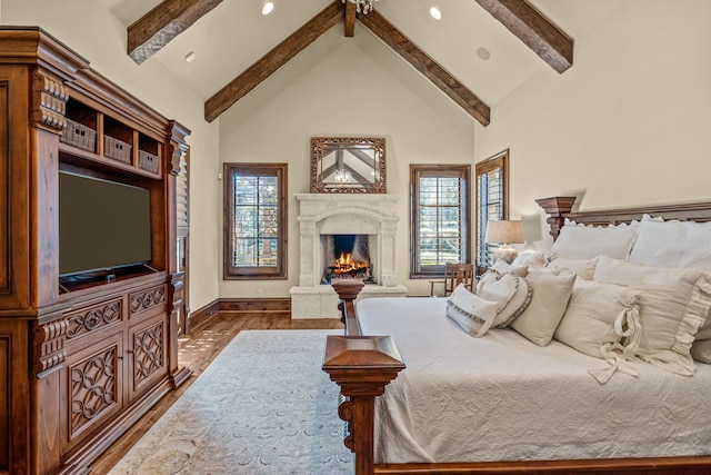 bedroom with beam ceiling, dark wood-type flooring, a fireplace, and high vaulted ceiling