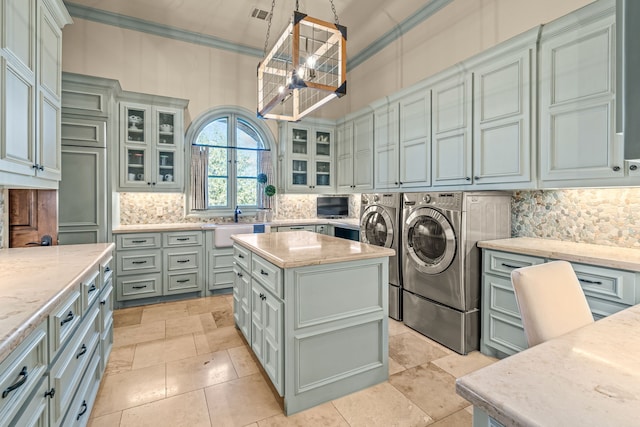 kitchen featuring light stone counters, washing machine and clothes dryer, decorative light fixtures, and a kitchen island