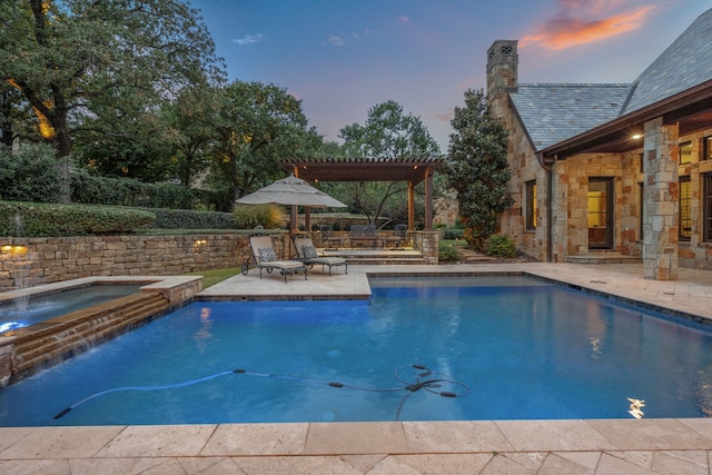 pool at dusk with an in ground hot tub, pool water feature, a patio, and a pergola