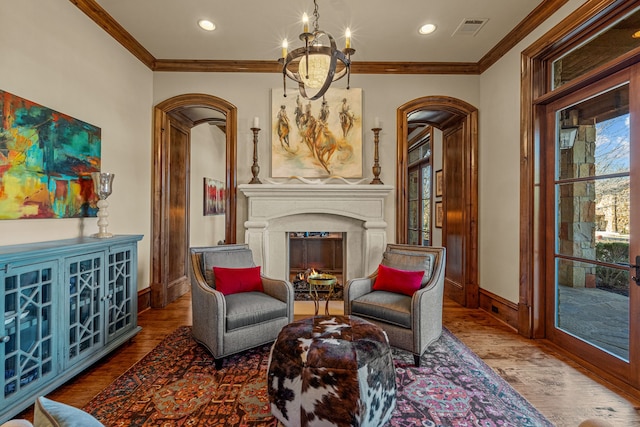 sitting room featuring hardwood / wood-style flooring, ornamental molding, and a notable chandelier