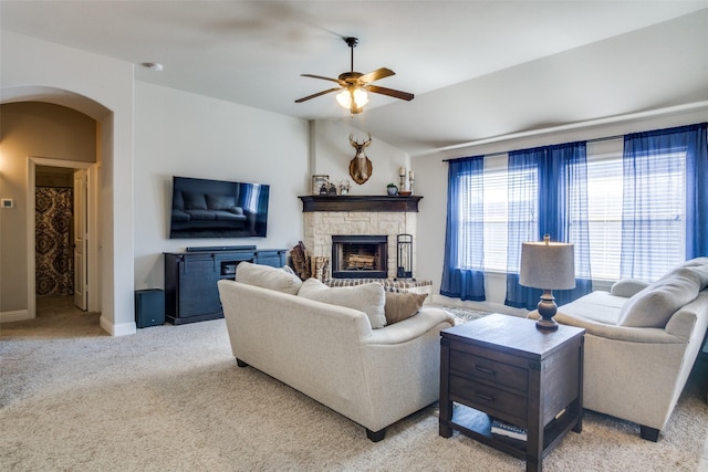 living room with a fireplace, light colored carpet, and ceiling fan