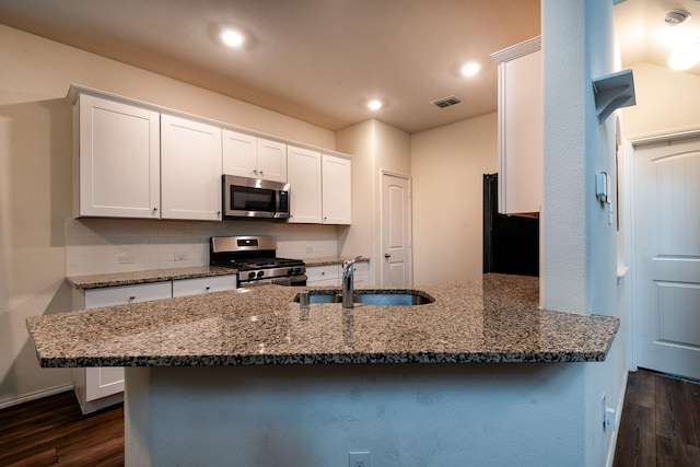 kitchen featuring dark stone countertops, appliances with stainless steel finishes, sink, and white cabinets