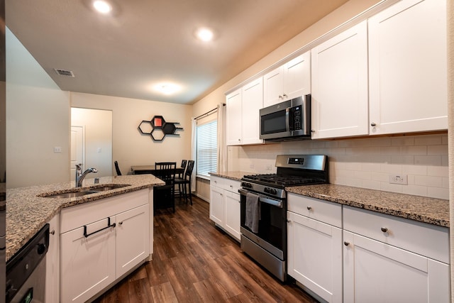 kitchen with stainless steel appliances, light stone countertops, sink, and white cabinets