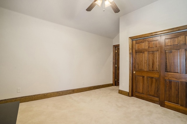 unfurnished bedroom featuring vaulted ceiling, carpet floors, ceiling fan, and a closet