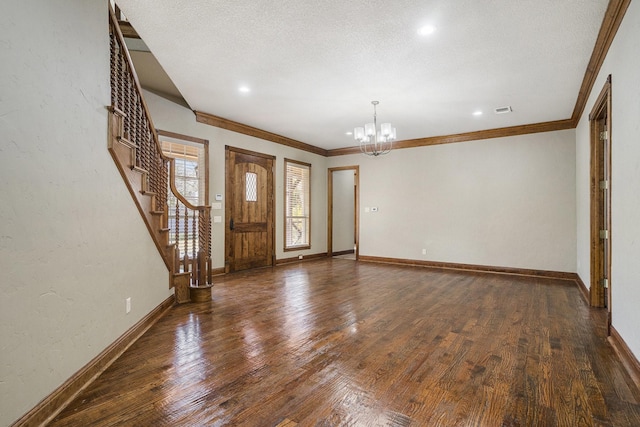 entryway featuring a textured ceiling, dark wood-type flooring, ornamental molding, and a chandelier