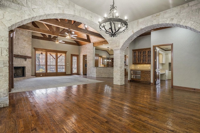 unfurnished living room featuring dark wood-type flooring, a fireplace, high vaulted ceiling, ceiling fan, and beam ceiling