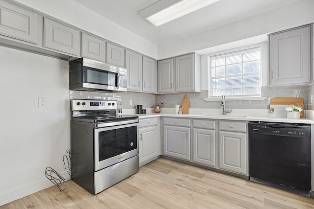 kitchen featuring sink, gray cabinets, stainless steel appliances, and light wood-type flooring