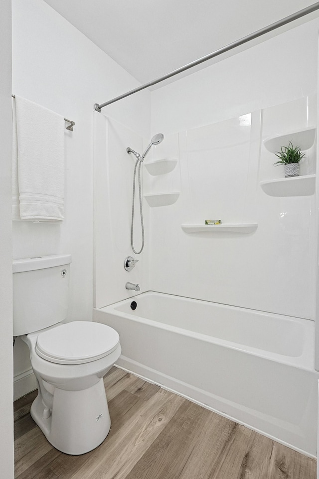 bathroom featuring hardwood / wood-style flooring,  shower combination, and toilet