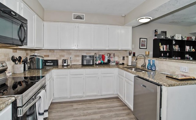 kitchen with white cabinetry, stainless steel appliances, kitchen peninsula, and sink