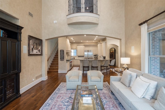 living room featuring a towering ceiling and dark wood-type flooring