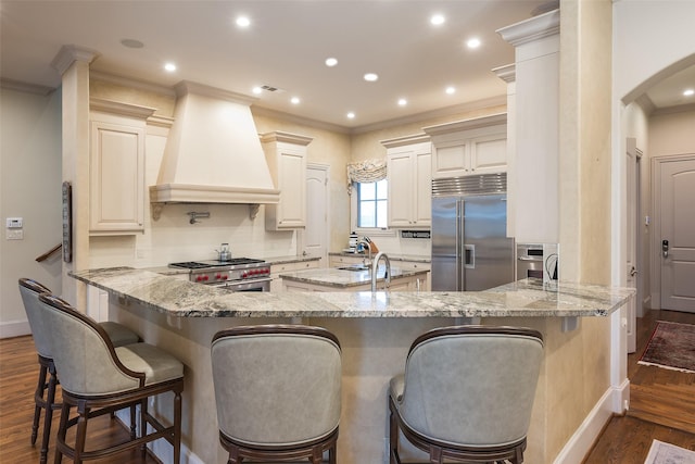 kitchen featuring custom exhaust hood, a kitchen breakfast bar, kitchen peninsula, and high quality appliances