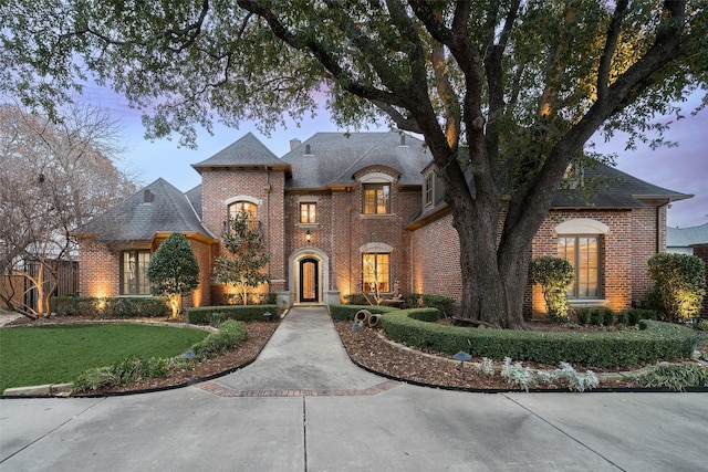 french country inspired facade featuring a yard