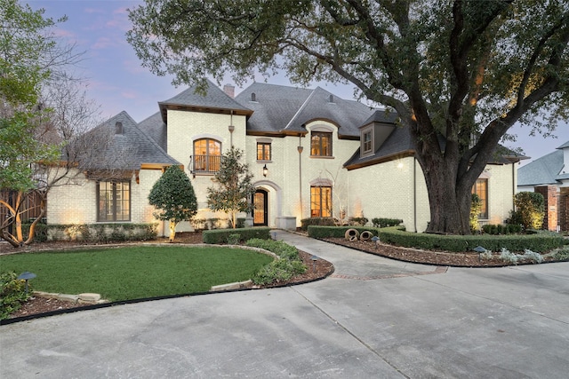 french provincial home with a lawn