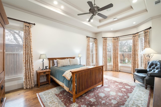 bedroom featuring a raised ceiling, wood-type flooring, crown molding, and ceiling fan