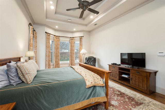 bedroom featuring ceiling fan, ornamental molding, a raised ceiling, and hardwood / wood-style floors