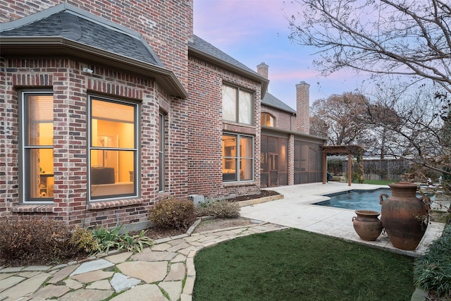 pool at dusk with a pergola and a patio area