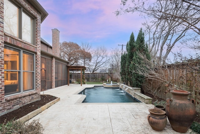 pool at dusk featuring pool water feature and a patio area