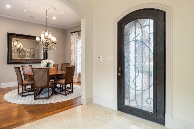 entrance foyer featuring crown molding, a healthy amount of sunlight, light wood-type flooring, and a notable chandelier