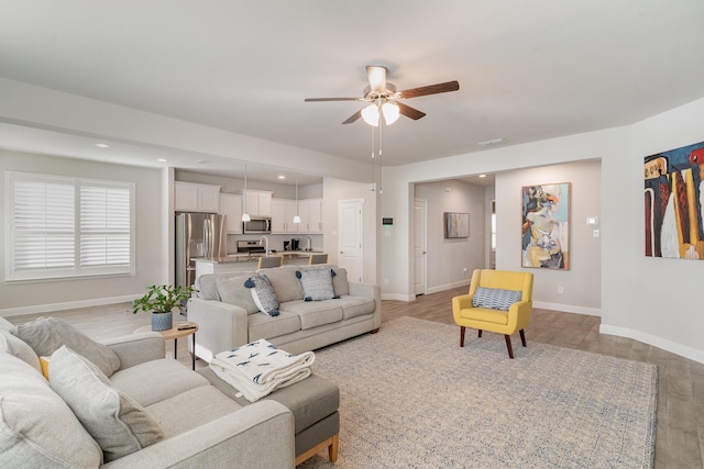 living room with light hardwood / wood-style floors and ceiling fan