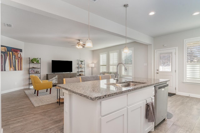 kitchen featuring sink, dishwasher, hanging light fixtures, light stone countertops, and white cabinets