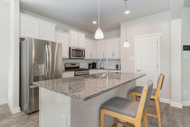 kitchen featuring sink, decorative light fixtures, dark stone countertops, appliances with stainless steel finishes, and white cabinets