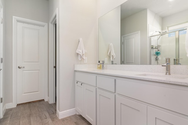 bathroom featuring wood-type flooring, a shower with door, and vanity