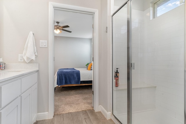 bathroom featuring vanity, hardwood / wood-style flooring, a shower with shower door, and ceiling fan